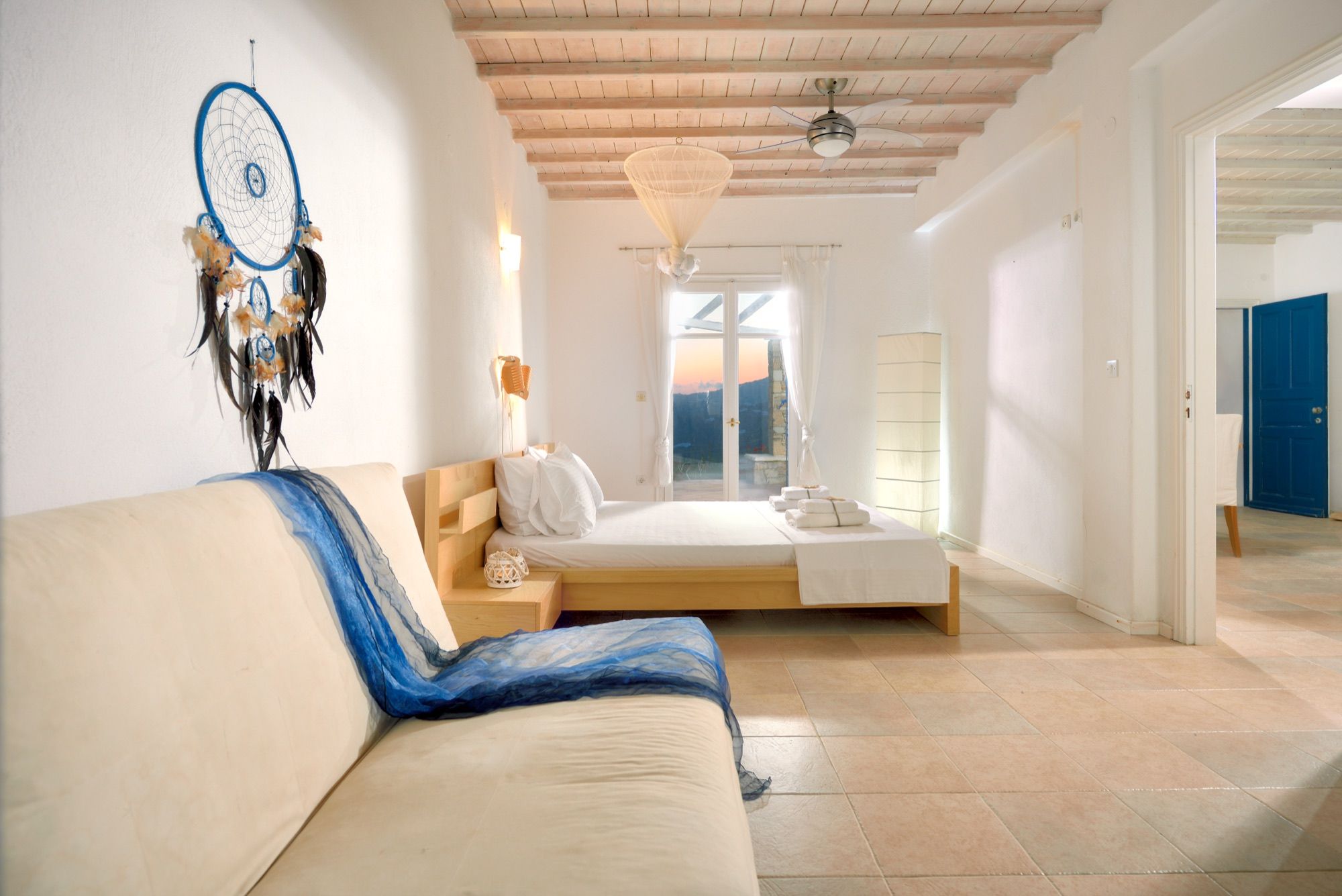 Bedroom with a sofa and a window framing the sea
