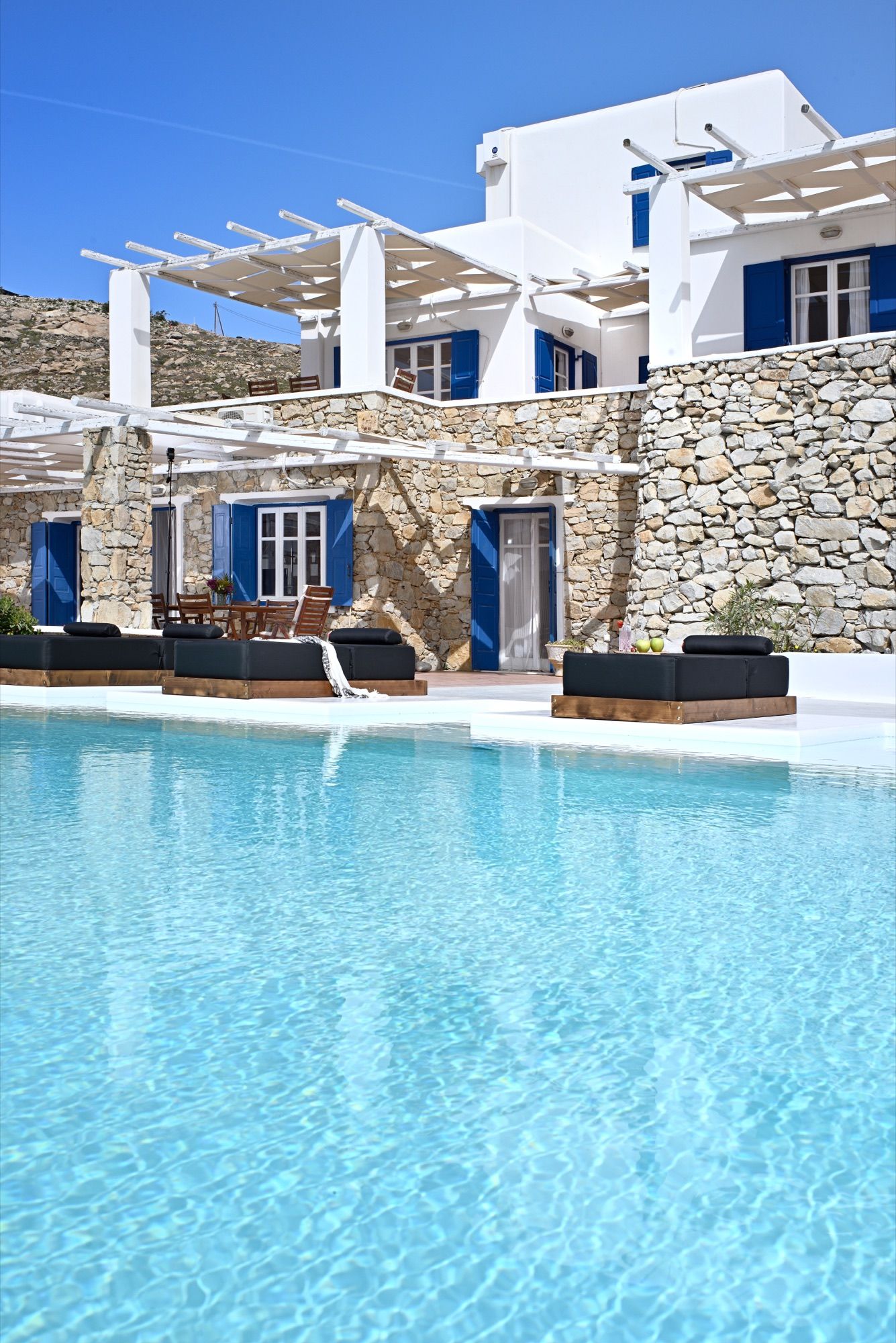 Whitewashed villa with blue shutters behind the pool