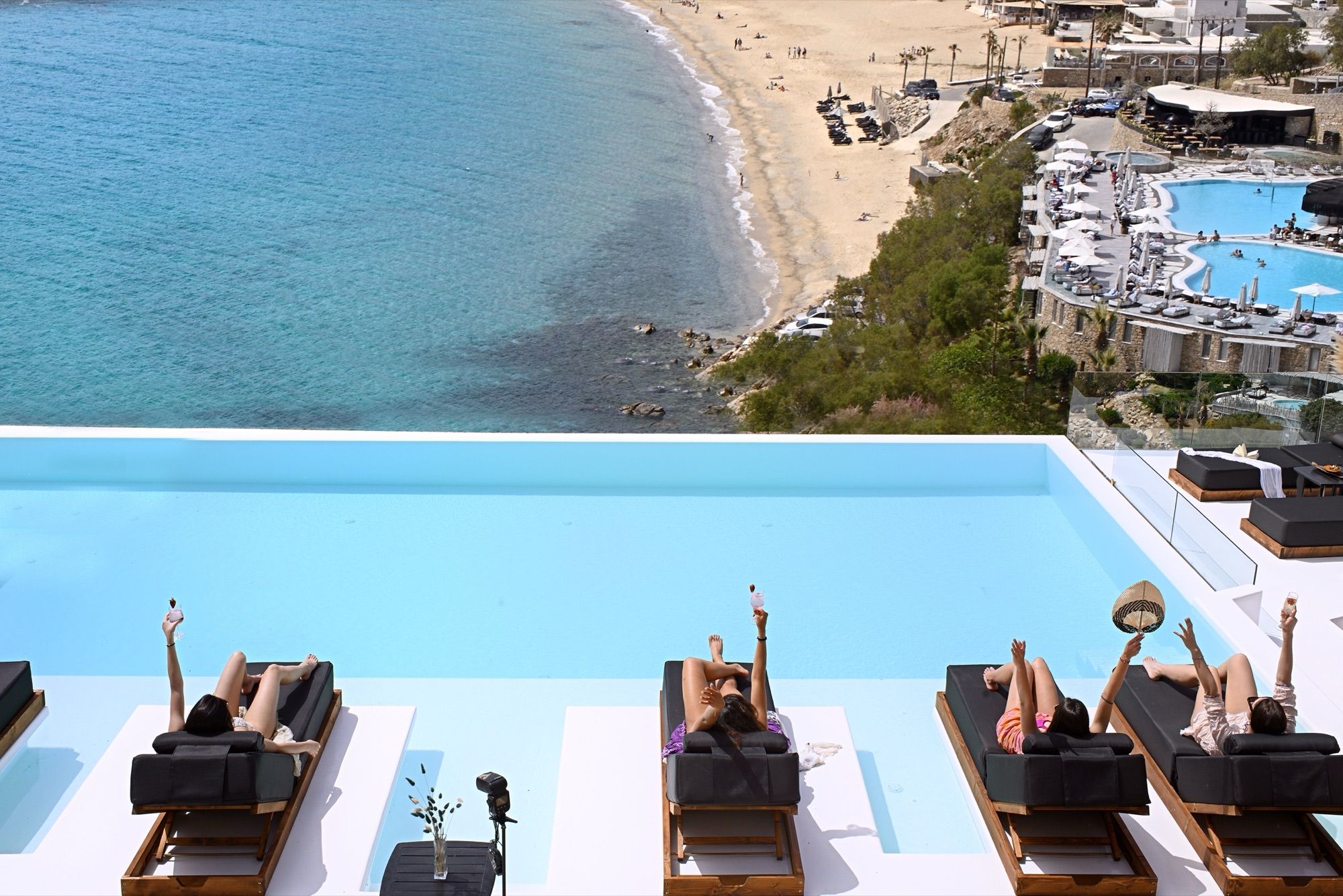 Guests on the sunbeds along the infinity pool with Elia Beach below