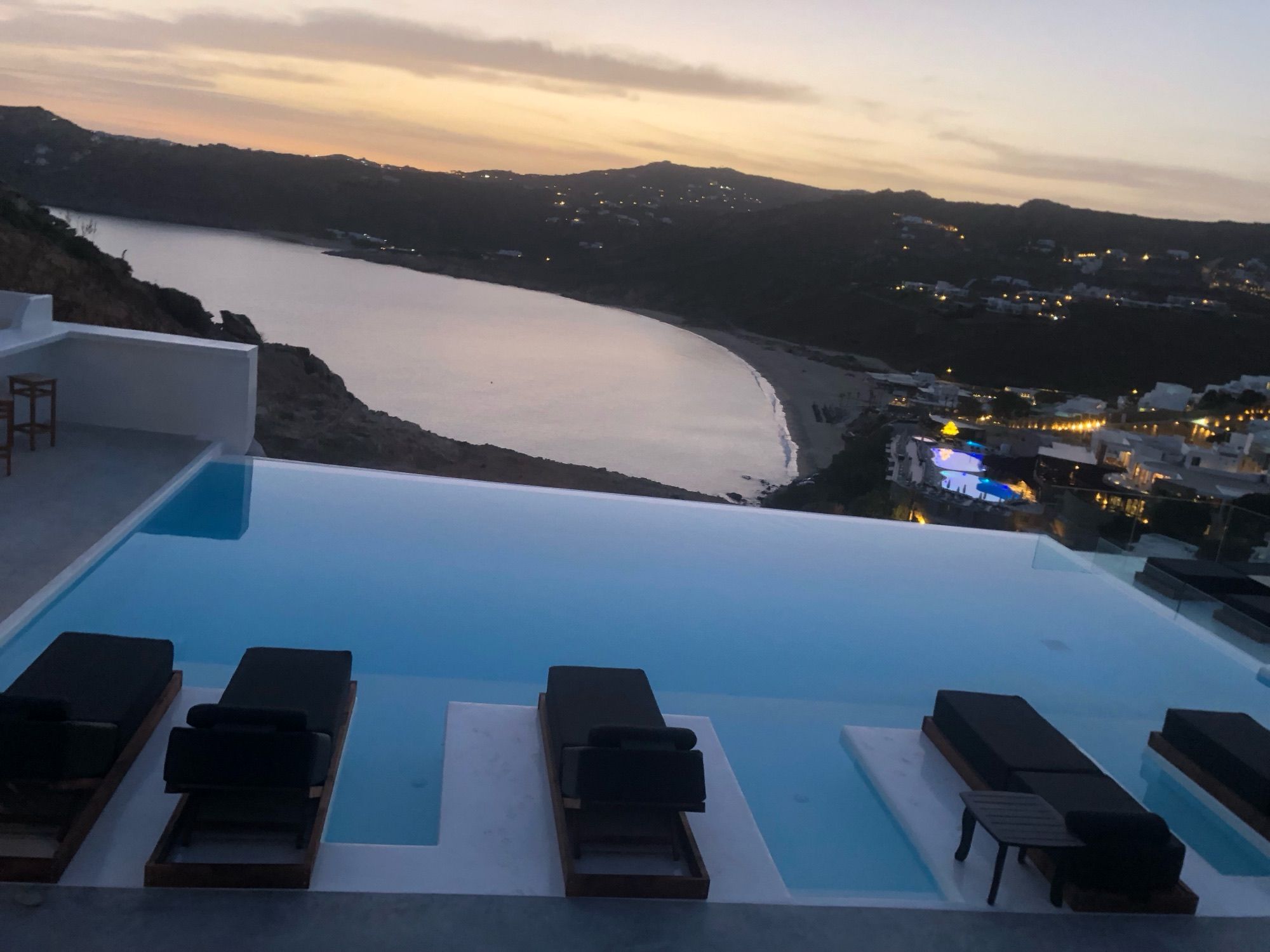 Sunbeds set in the infinity pool at dusk, above Elia Bay