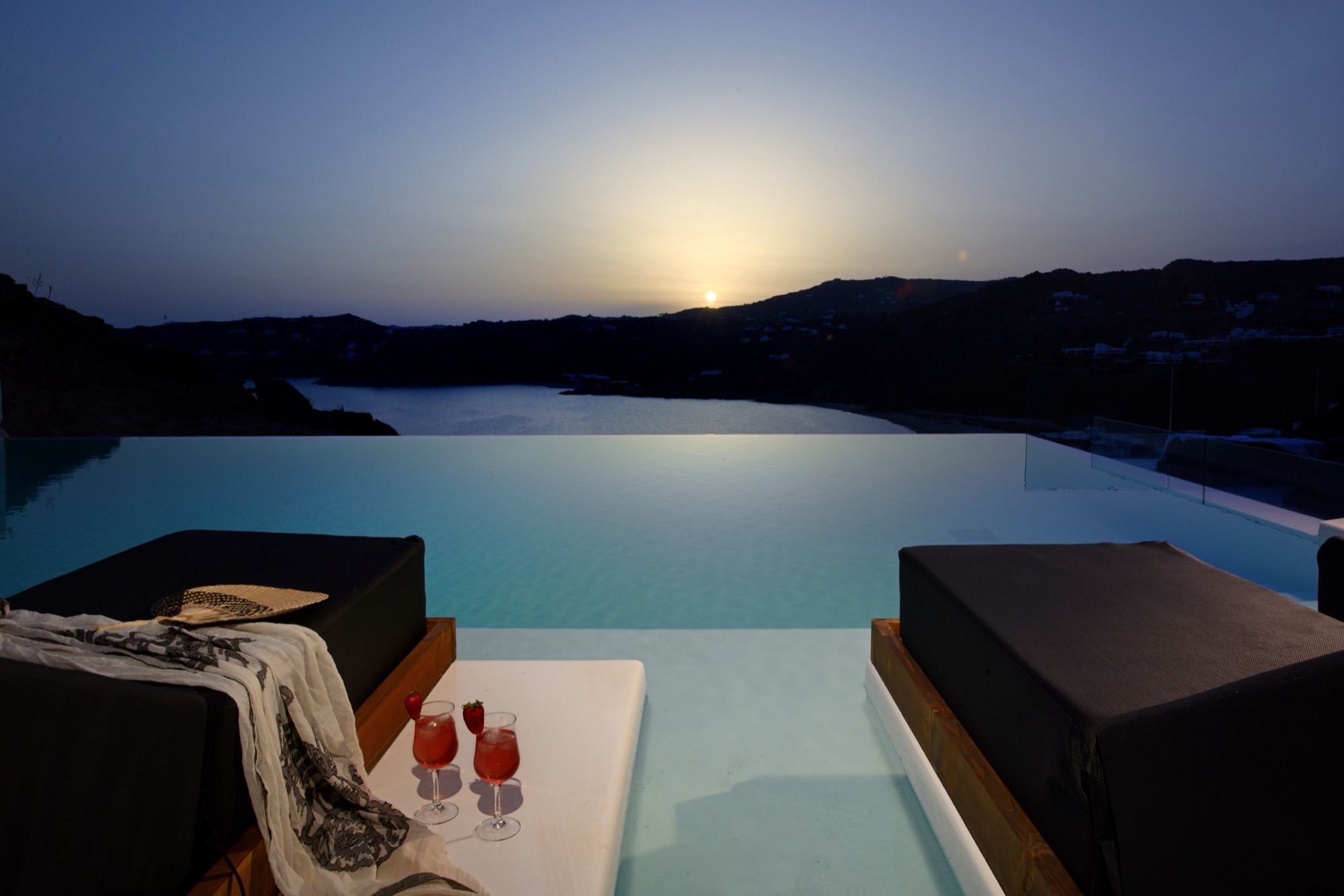 Two in-pool sunbeds and drinks at the infinity edge as the sun sets over the hills of Elia bay