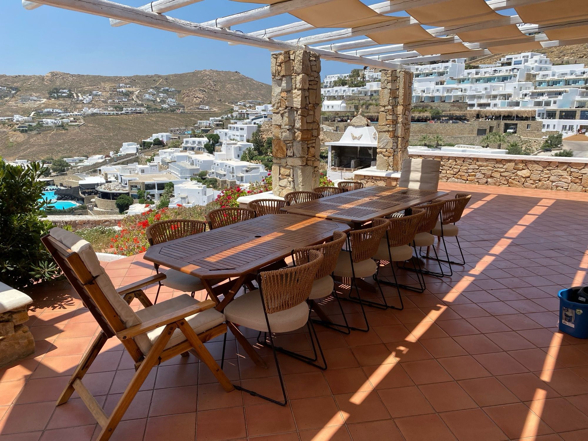 Long dining table with seating for a large group under the pergola, overlooking the Elia hillside