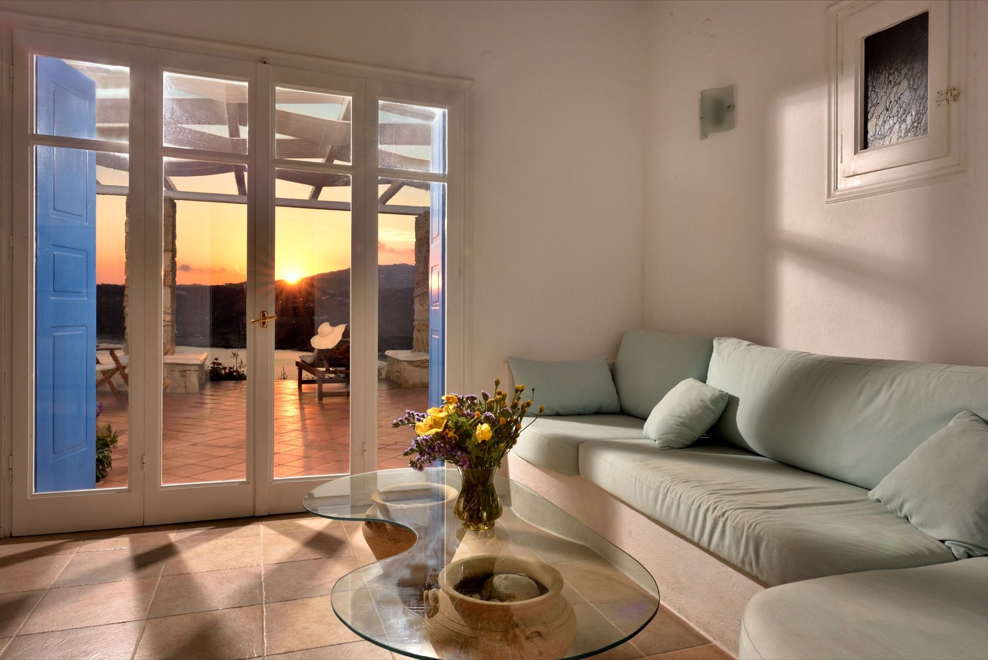 Lounge with a built-in sofa and glass doors opening onto the terrace at sunset