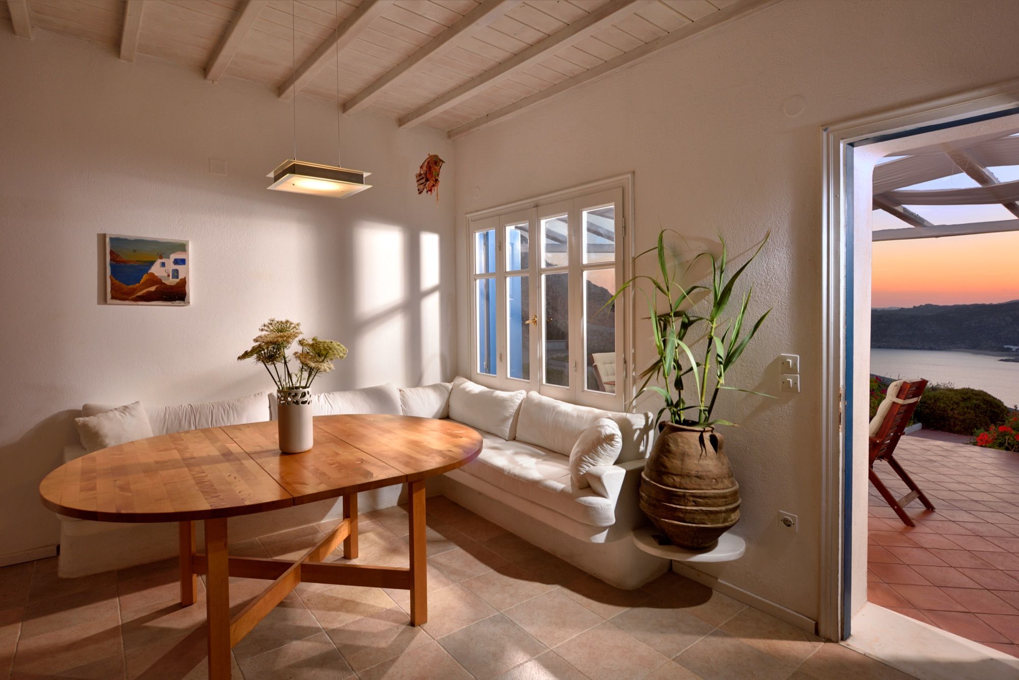 Living room with a round dining table and doors open to the sunset
