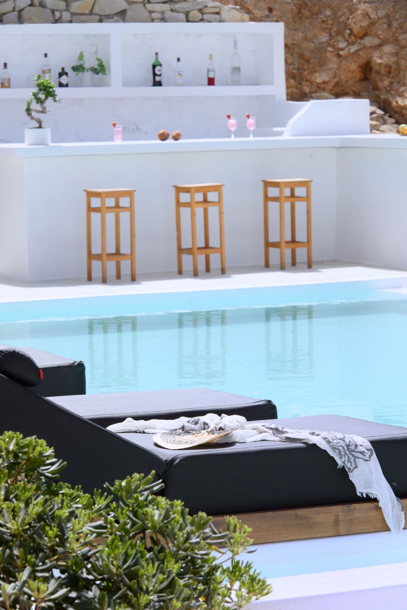 White built-in pool bar with wooden stools at the edge of the pool