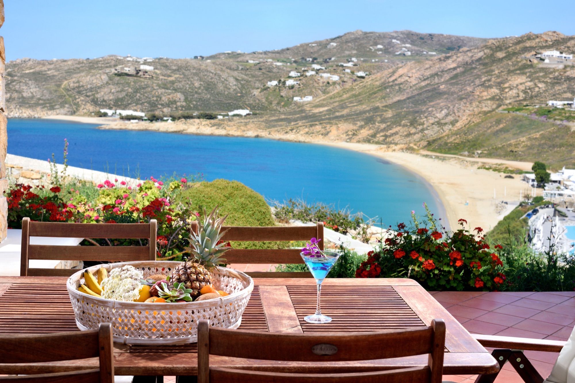 Terrace table set with fresh fruit and drinks above the bay