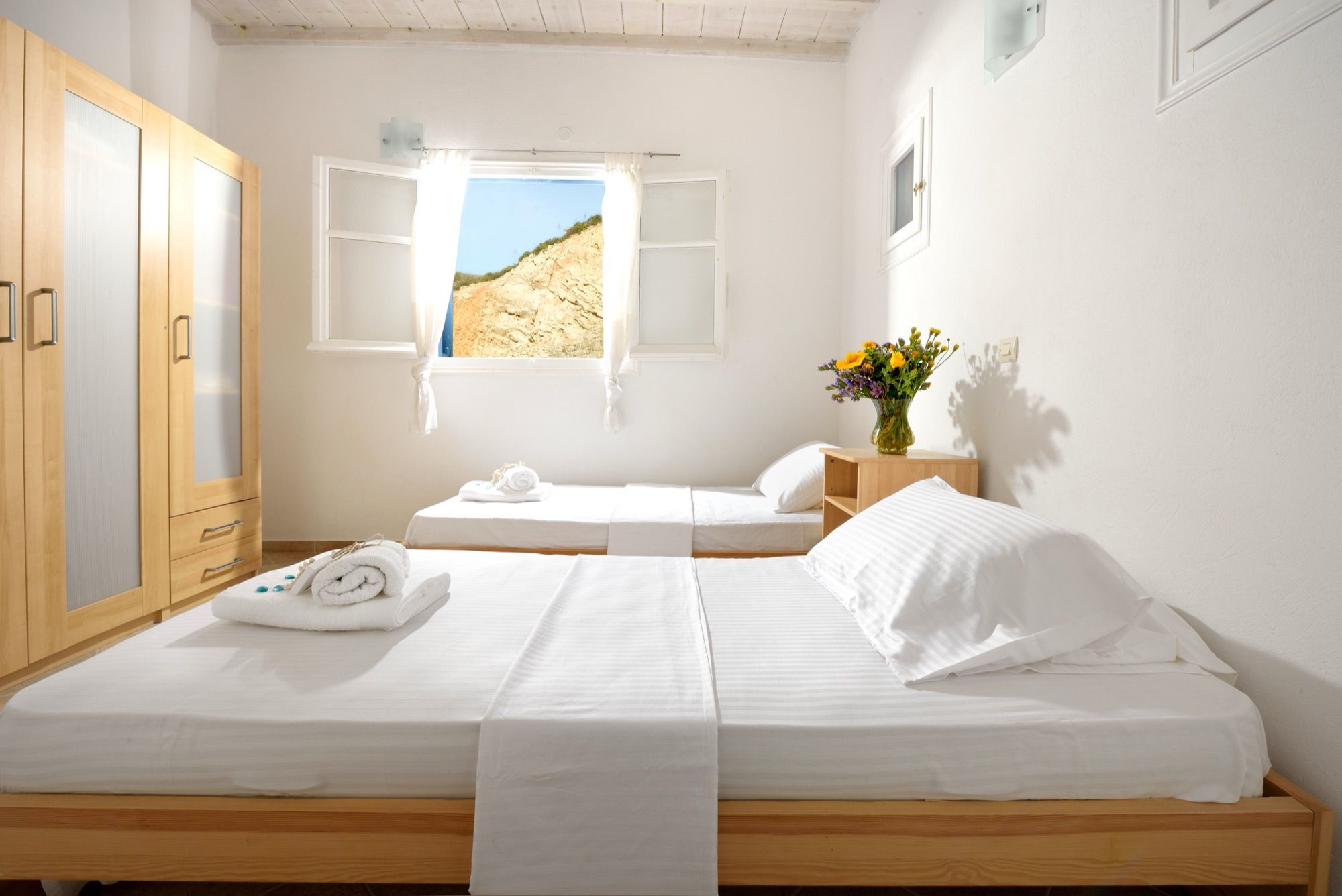 Bedroom with a double bed, a single bed and a wooden wardrobe